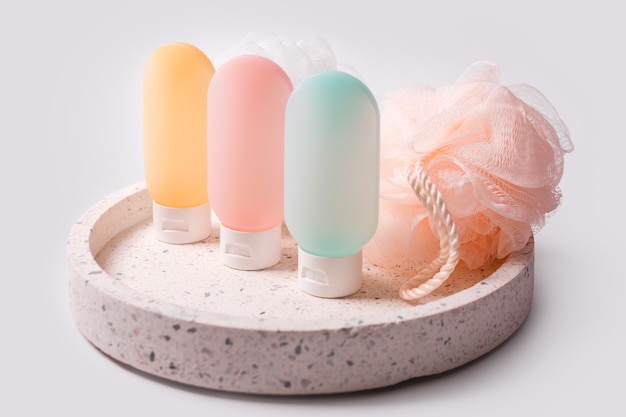 Kleurrijke plastic bakjes voor shampoo, haarbalsem en douchegel met washandjes op een marmeren dienblad.