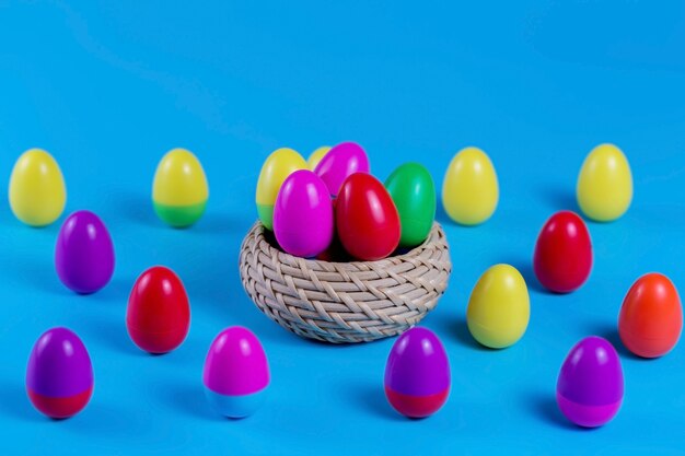 Kleurrijke Plastic Easter Eggs in een rieten mand op blauwe achtergrond.