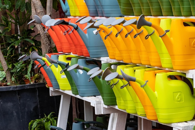 Kleurrijke plastic gieters op een plank in een tuinwinkel.