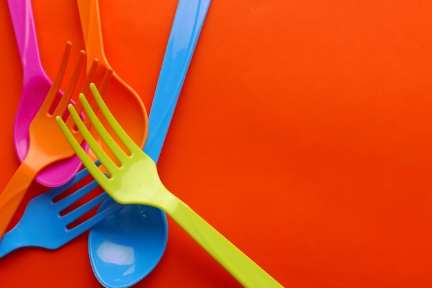 Kleurrijke plastic lepel die op oranje achtergrond wordt geïsoleerd.