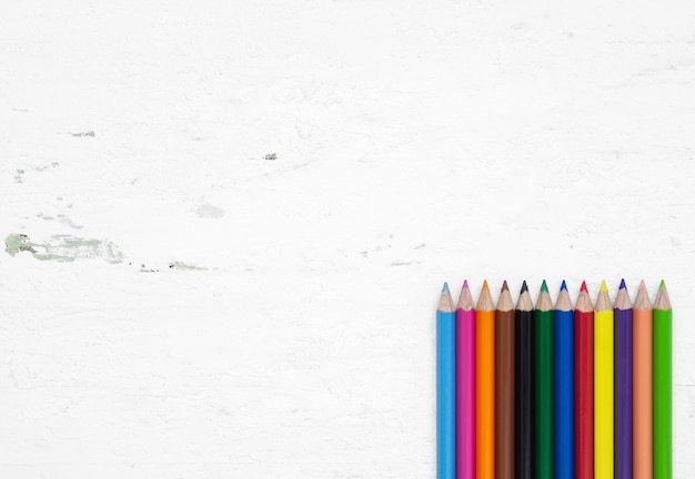 Kleurrijke potloodkleurpotloden op een grunge witte houten achtergrond met lege ruimte