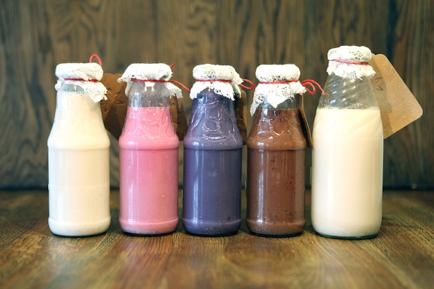 Kleurrijke Smoothies bij flessen Kleurrijke drink milkshake in fles met verse groenten op hout