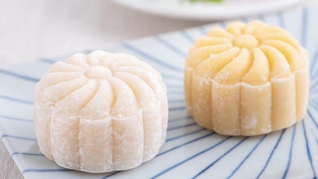 Kleurrijke sneeuw huid maancake, zoete besneeuwde mooncake, traditioneel hartig dessert voor Mid-Autumn Festival op lichte houten achtergrond, close-up, levensstijl.