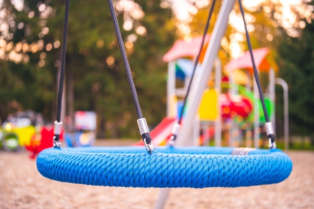 Kleurrijke speelplaats op het erf in het park Kleurrijke speelplaatsactiviteiten voor kinderen in openbaar park omgeven door groene bomen