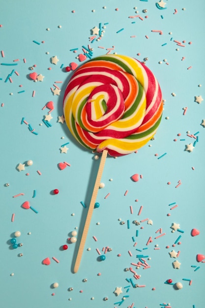 Kleurrijke spiraal lolly met besprenkeling op blauwe achtergrond. Verticale foto