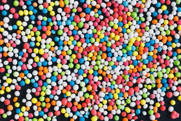 Kleurrijke suikerballen gestrooid op donkere grunge metalen achtergrond bovenaanzicht
