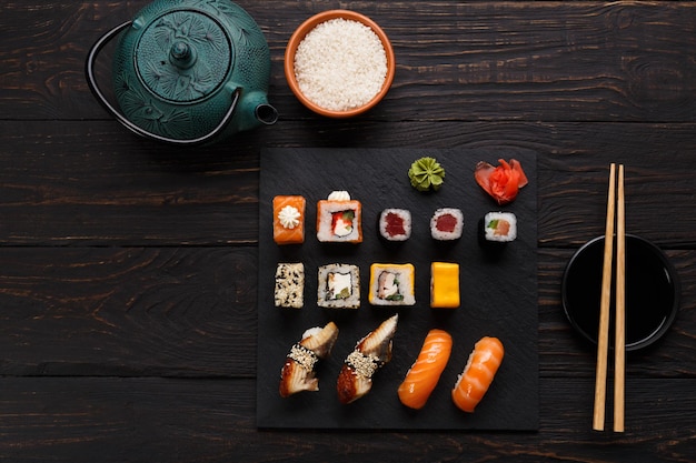 Kleurrijke sushi en broodjesschotel in Japans restaurant, met theepot en eetstokjes bovenaanzicht.