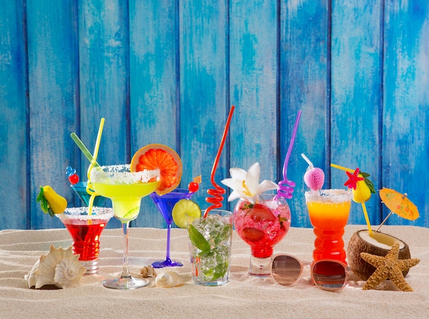 Kleurrijke tropische cocktails op strand op blauwe houten muur