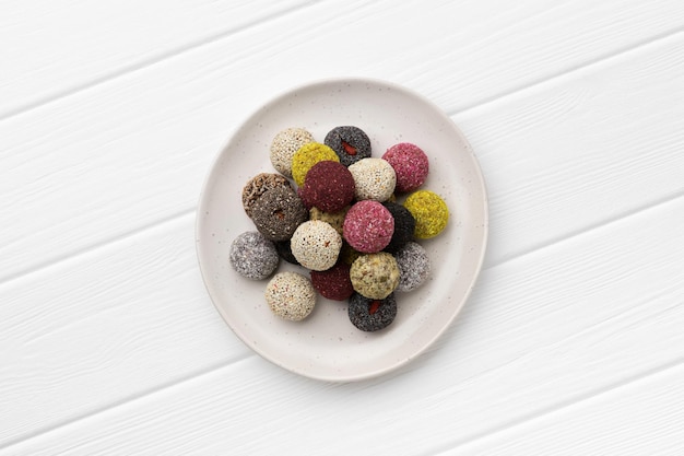 Kleurrijke veganistische snoepjes energieballen op een bord op een witte tafel