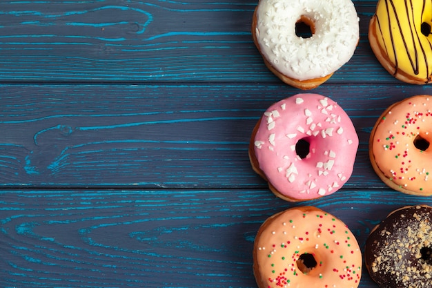 Kleurrijke verse donuts op donkerblauwe houten achtergrond