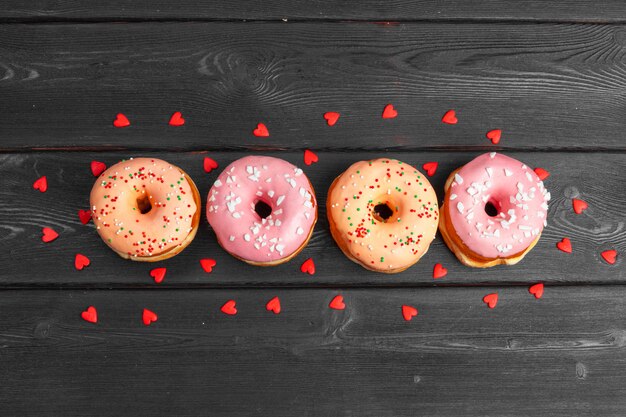 Foto kleurrijke verse donuts op donkere zwarte houten oppervlak