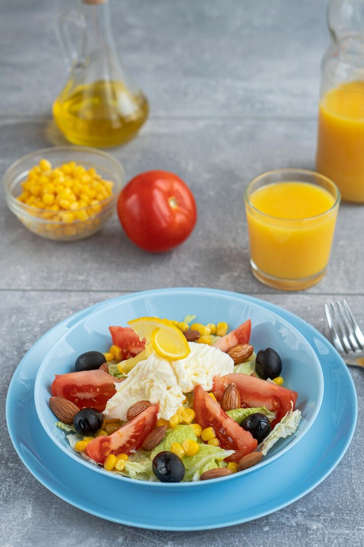 Kleurrijke verse groentensalade met mozzarella kaas in een schaal en sinaasappelsap Gezond voedselconcept
