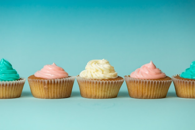 Foto kleurrijke versgebakken cupcakes in rij over blauwe achtergrond