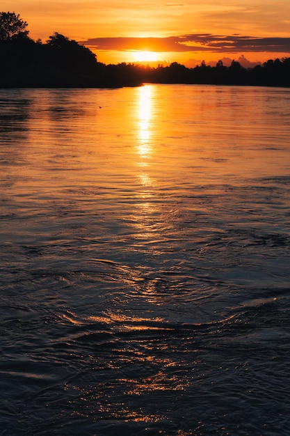 Kleurrijke zonsondergang schijnt op tropisch bos en rivier op het platteland