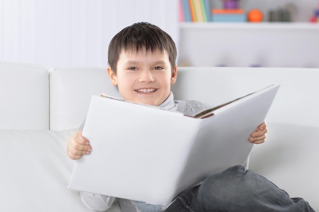 Kleuter die een boek leest op de bank in de kinderkamer