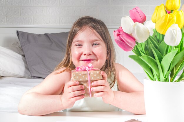 Kleuter kind peuter blond meisje met een boeket van tulp bloemen en de kopie ruimte van de geschenkdoos