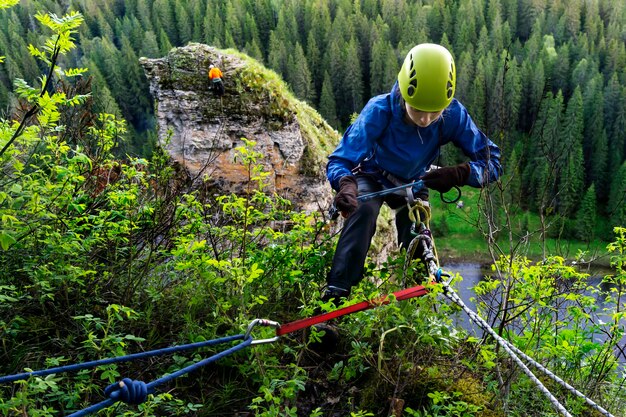 Klimmeisje controleert de veiligheidsuitrusting terwijl ze zich voorbereidt om van de klif boven de rivier af te dalen