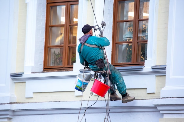 Klimmende arbeider die ramen en de gevel van een gerenoveerde woningbouwsector schoonmaakt