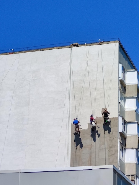 Klimmers die de gevel van een woongebouw in rusland repareren - achteraanzicht.