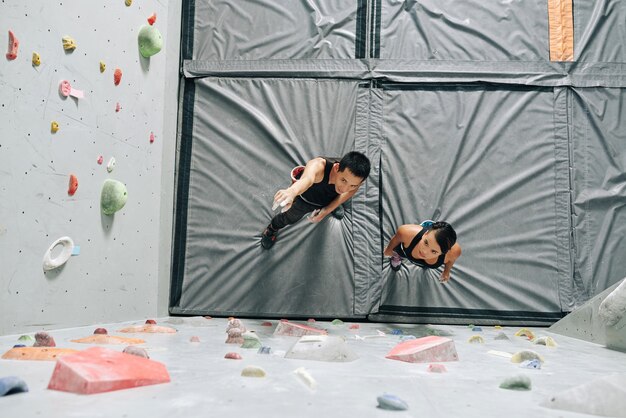 Klimmuurinstructeur die jonge vrouw uitlegt hoe ze de bouldermuur moet beklimmen, uitzicht vanaf de top