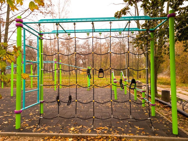 Foto klimnet en moderne fitnessapparatuur voor training op een leeg sportveld in een stadspark op een mistige herfstochtend