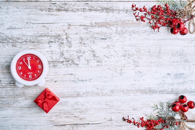 Klok op de achtergrond op een houten tafel versierd met een slinger en rode kerstballen voor het nieuwe jaar of XMAS. Ruimte kopiëren