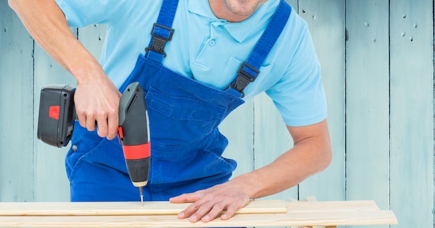 Klusjesman boren houten plank met boormachine