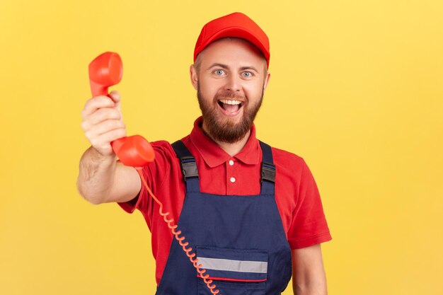 Klusjesman in blauw uniform die de handset vasthoudt en hem vraagt hem te bellen en service te bestellen