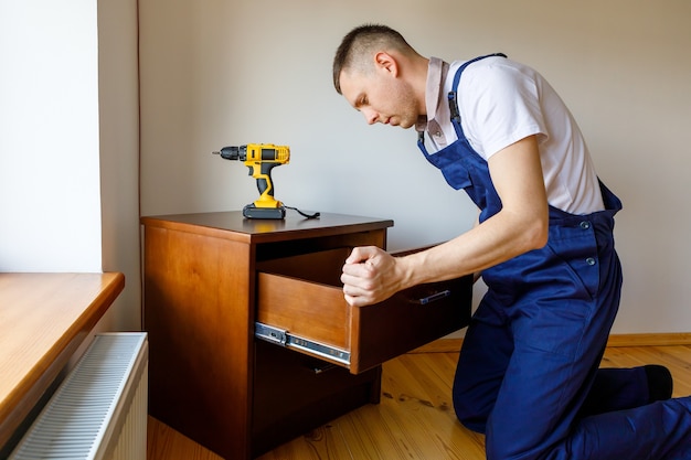 Klusjesman in blauw uniform werkt met automatische schroevendraaier elektriciteit. Huis renovatie conceptie.