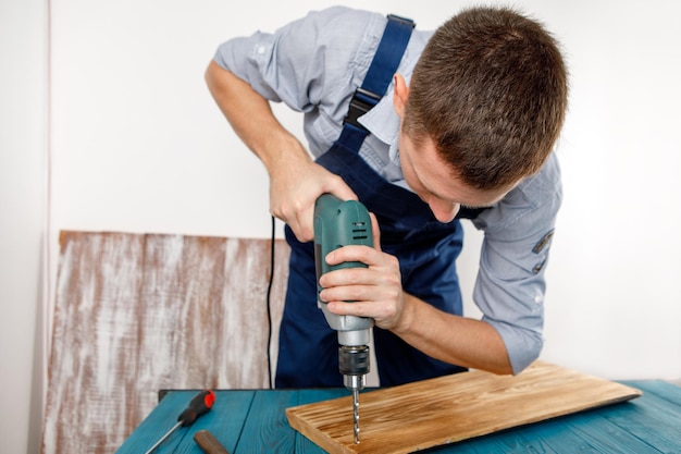 Klusjesman in blauw uniform werkt met elektriciteit automatische schroevendraaier huisrenovatie concept