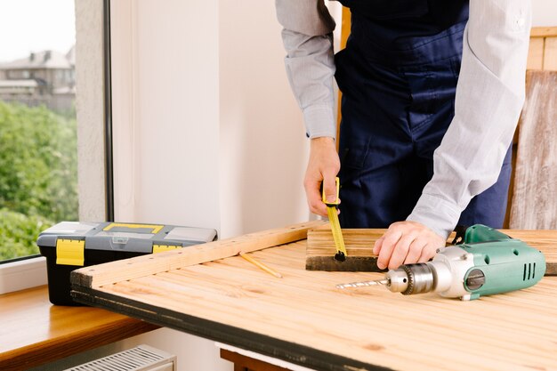 Klusjesman in blauw uniform werkt met elektrische automatische schroevendraaier. Huis renovatie concept.