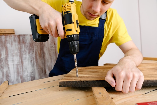 Klusjesman in blauw uniform werkt met elektrische automatische schroevendraaier Huisrenovatieconcept