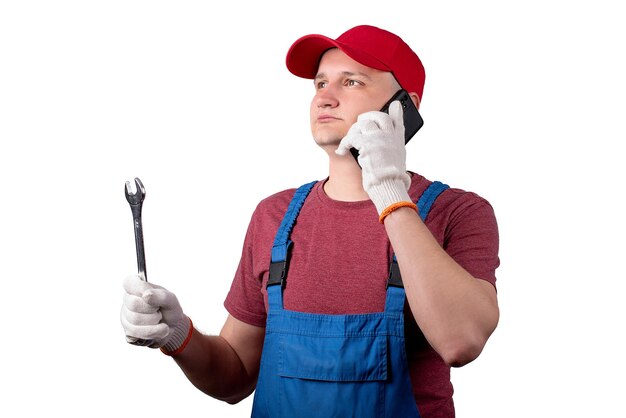 Klusjesman met een moersleutel en een telefoon op een witte achtergrond in een werkuniform en een pet het concept van het bellen van de meester naar de housexA