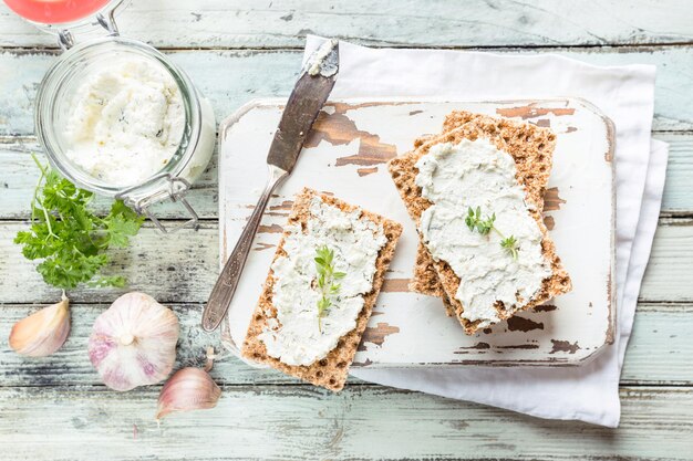 Knäckebröd toast met zelfgemaakte kruiden en knoflook kwark op houten ondergrond, bovenaanzicht