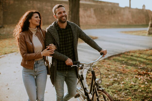 Knap jong stel dat met de fiets in het herfstpark loopt