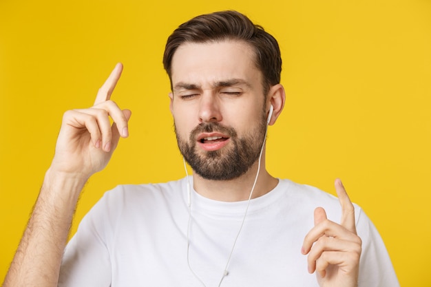 Knap van een jonge man die geniet van muziek op gele achtergrond.