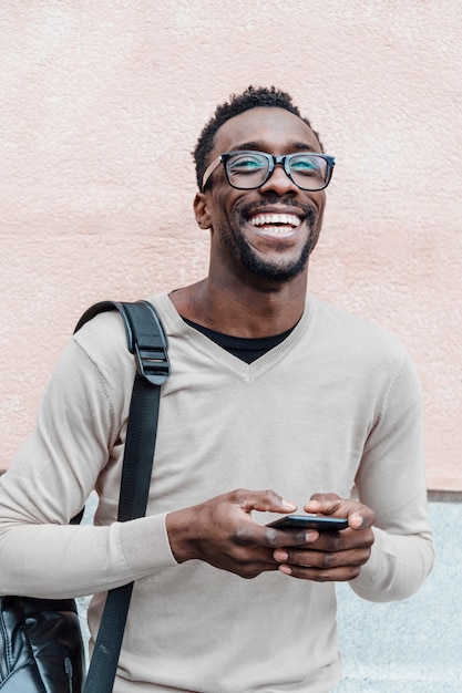 Knappe Afro-Amerikaanse man die lacht met smartphone