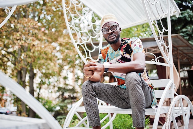 Knappe Afro-Amerikaanse man met een traditionele kledingpet en een bril die aan een witte koets zit