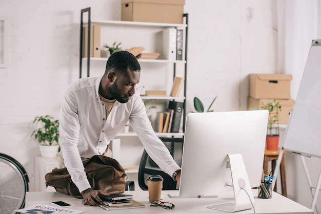Foto knappe afro-amerikaanse zakenman met behulp van computer op kantoor