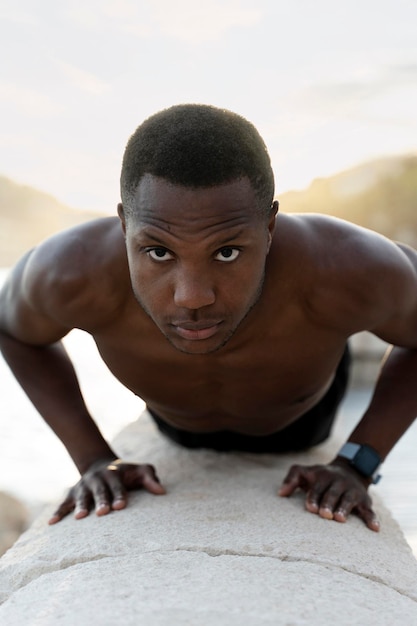 Knappe atletische man van gemengd ras met gespierd lichaam die push-ups doet