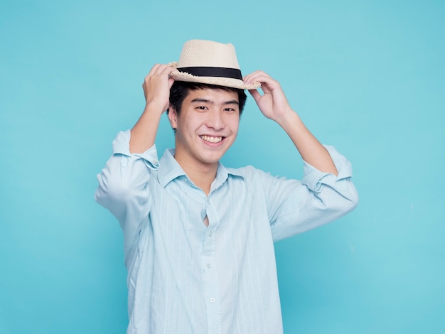 Knappe Aziatische man in een blauw shirt met een hoed