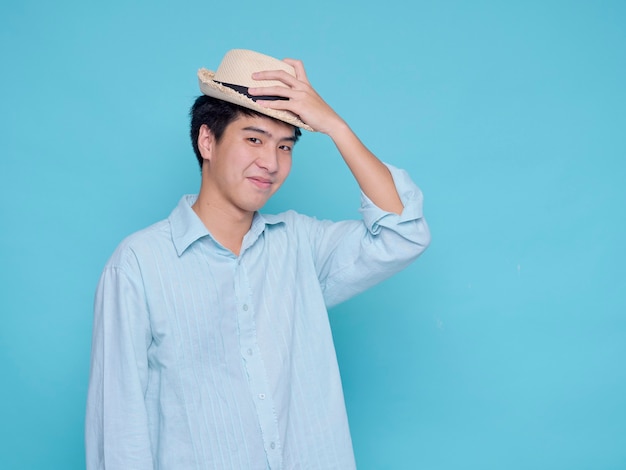 Knappe Aziatische man in een blauw shirt met een hoed