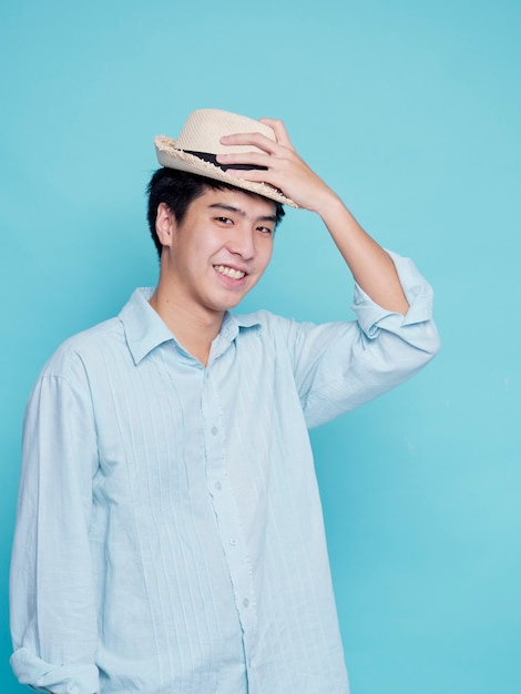 Knappe Aziatische man in een blauw shirt met een hoed