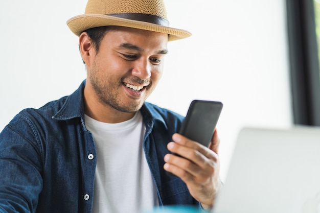 Knappe Aziatische man thuis werken met smartphone