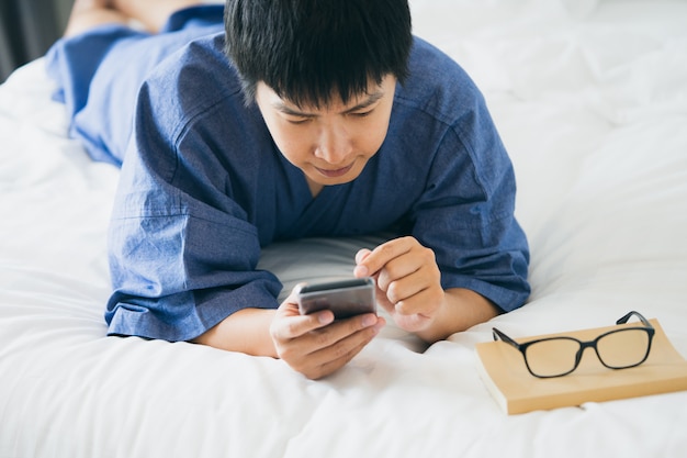 Knappe Aziatische mannen die op een smartphone slapen. Speel op de media.