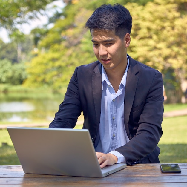 Knappe Aziatische zakenman die laptop met behulp van