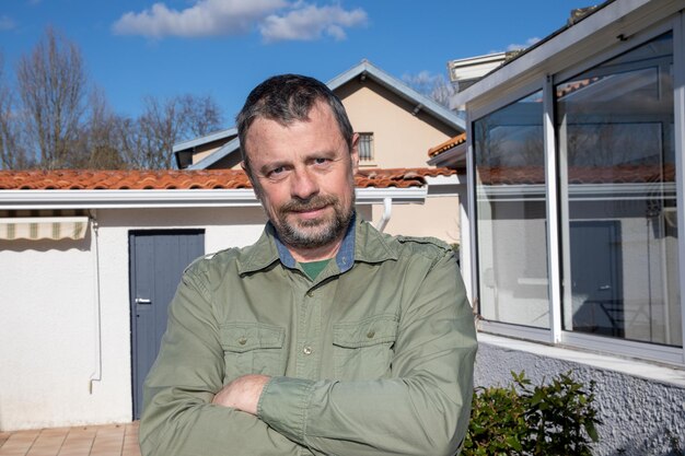 Knappe baard man van middelbare leeftijd buiten glimlachend in huis tuin eigendom