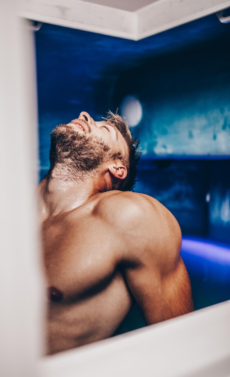 Foto knappe baardman drijvend in tank gevuld met dicht zout water dat wordt gebruikt in meditatie, therapie en alternatieve geneeskunde.