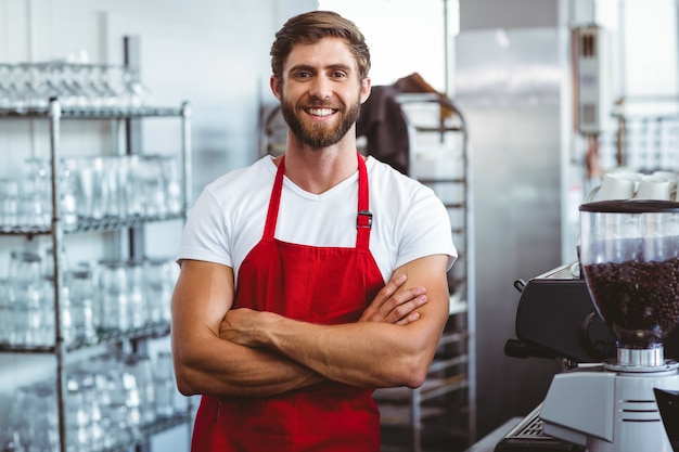 Knappe barista die bij de camera glimlacht