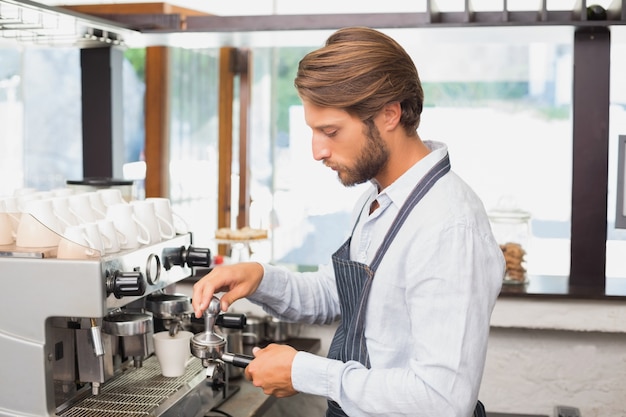 Knappe barista die een kop van koffie maakt